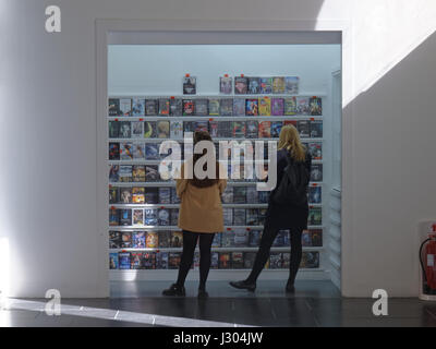 Zwei Mädchen, die Auswahl von DVDs in Glasgow GOMA Stockfoto