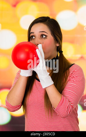 Closeup Portrait von junge Mädchen Clown-Mime bläst einen Ballon Stockfoto