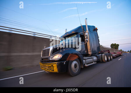 Leistungsstarke und effektive moderne schwarze LKW mit Chromrohren und große Größe Zeichen übergroße Last auf gelben Vinyl-Stoff an der vorderen Stoßstange befestigt Stockfoto