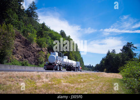 Semi Truck Big Rig mit Länge Tank transportiert gefährliche Stoffe regelmäßige Flüge mit Erlaubnis auf der Autobahn in der schönen Aussicht zu transportieren Stockfoto