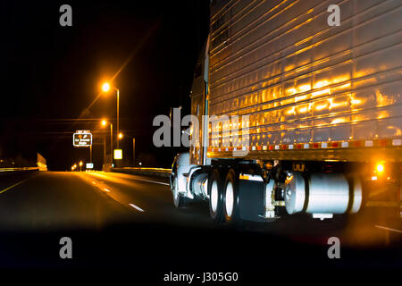 Classic Big Rig Semi Truck mit hellen reflektierende Auflieger läuft in der Nacht High Way imit Licht. Stockfoto