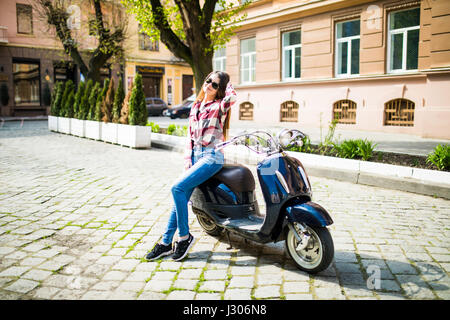 Junge und schöne Frau Reiten Roller entlang der Straße Stockfoto