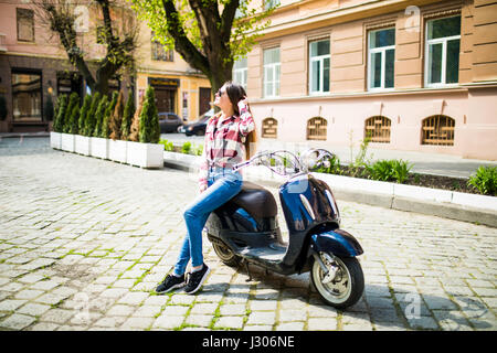 Junge und schöne Frau Reiten Roller entlang der Straße Stockfoto