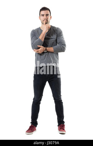 Lustige junge konzentriert Mann beobachten und Augen Schielen. Ganzkörper-Länge-Porträt über weiße Studio-Hintergrund isoliert. Stockfoto