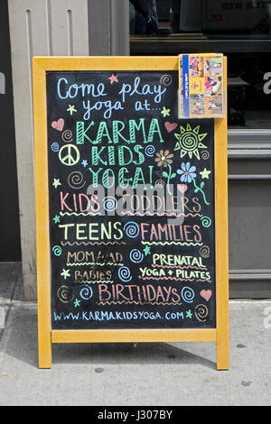 Eine Tafel Werbung für Karma-Kinder-Yoga, Yoga-Studio, das Yoga für Kinder spezialisiert. Auf West 23rd St. im Abschnitt Chelsea von New York City. Stockfoto