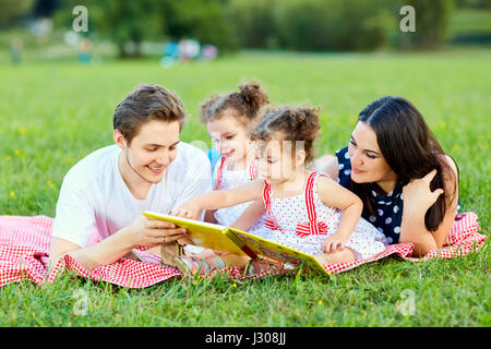 Eine glückliche Familie liest Buch im park Stockfoto