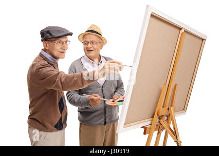 Zwei glückliche reife Männer malen auf einer Leinwand isoliert auf weißem Hintergrund Stockfoto