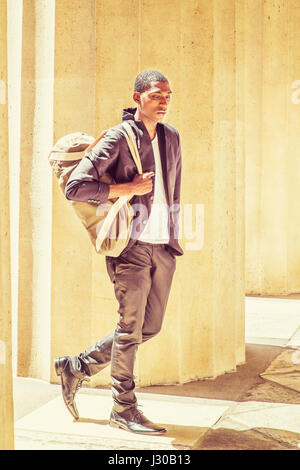 African American Jüngling in New York zu reisen, Schulter-Tragetasche, wandern aber Spalten auf dem Campus, blickte, denken. Street Fashion. Ins Stockfoto