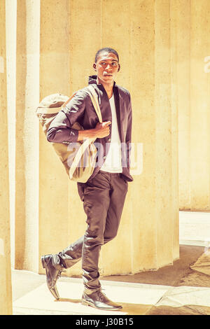 African American Jüngling in New York zu reisen, Schulter-Tragetasche, wandern aber Spalten auf dem Campus, getrost freuen. Street Fashion Stockfoto