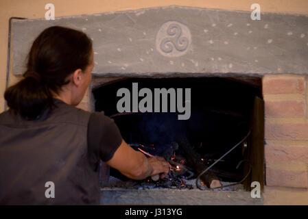 Frau stellt sich auf das Feuer von einem Holzofen Stockfoto