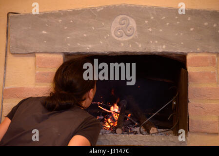 Frau stellt sich auf das Feuer von einem Holzofen Stockfoto