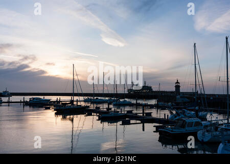 England, Ramsgate Hafen. Sonnenaufgang über den Wolken am Horizont die Silhouette von Yachten und Boote zum Jachthafen, mit Reflexionen. blaue Farbe Licht. Stockfoto