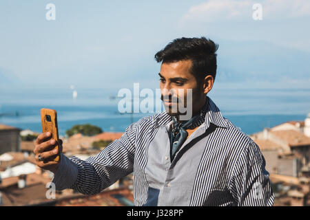 Schöner indischer Mann nimmt ein Selbstporträt in einem Urlaub-Kontext. Street-Fashion und Style. Stockfoto