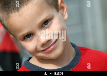 Nahaufnahme des kleinen Jungen zeigt die Sommersprossen bestreut über seine Nase.  Er ist kippen den Kopf und grinste. Stockfoto