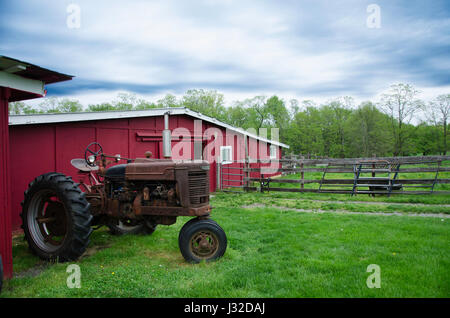 Ein Retro-Traktor parkte neben einer Scheune. Stockfoto