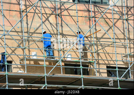 Zwei Männer stehen auf Gerüsten und arbeiten am äußeren Reparaturen am Gebäude Stadt in der Innenstadt, Asheville, North Carolina. Stockfoto