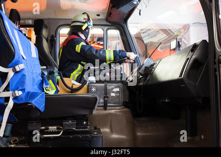Deutsche Feuerwehr fährt in ein Feuerwehrauto in Aktion und verwendet ein Walkie-Talkie