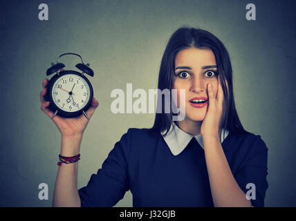 Ängstliche junge Frau mit Wecker. Zeit-Druck-Konzept. Menschliche Emotionen Gesicht Ausdruck Stockfoto