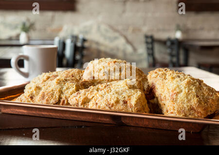 Scones, die Kühlung auf ein Backblech legen, mit einer Tasse Kaffee in einem Restaurant, Café oder Bäckerei Stockfoto