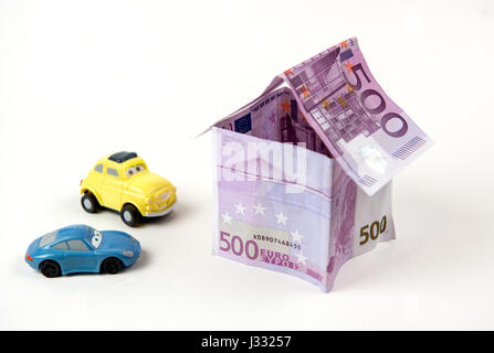 Haus mit 500 Euro-Banknoten und Autos parkten außerhalb isoliert auf weißem Hintergrund Stockfoto