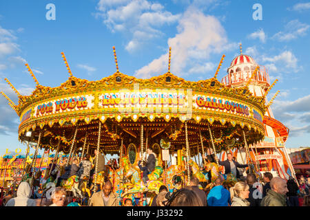 Massen von Menschen um einen traditionellen Messe fahren. Ein Merry go round in der Abendsonne an Goose Fair, Nottingham, England, Großbritannien Stockfoto