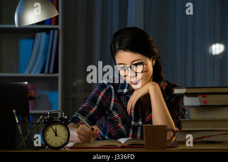 Schweren asiatischen jungen Studenten studieren mit Bücher und Computer im dunklen Raum zu Hause. Gemischte Rassen asiatische chinesische Modell. Stockfoto