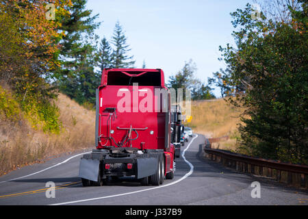 Eine Säule von mehreren modernen Sattelschlepper ohne Anhänger mit Spoiler und Kotflügel, zusammen mit den anderen Autos bewegen sich entlang einer kurvenreichen Straße durch Stockfoto