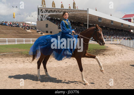 Eine kirgisische Mädchen gekleidet in blau auf ein Rennpferd bei einer Veranstaltung von Pferderennen auf der Welt Nomad Spiele 2016 in Cholpon Ata, Kirgisistan Stockfoto