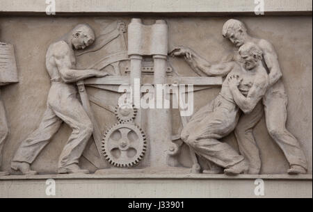 Unfall in der Druckerei. Relief von dem ungarischen Bildhauer Gyula Maugsch (1930) am Nordflügel des Art-Déco-Gebäudes von Budapest Arbeitnehmer Krankenkasse in Budapest, Ungarn. Das Gebäude, nun als Sitz der nationalen Sozialversicherung Zentrum (OTI), wurde von ungarischen Architekten Marcell Komor und Dezsö Jakab entworfen und im Jahre 1913 gebaut. Der Nordflügel wurde vom Architekten Aladar Sos 1930-1931 hinzugefügt. Stockfoto