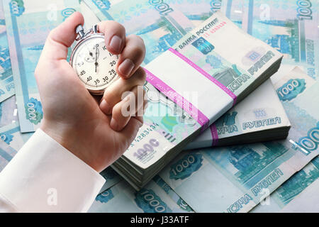 Geld im Wrapper und Stoppuhr in männlicher hand Stockfoto