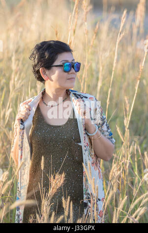 Porträt der Asiatin mit Sonnenbrille stehend entspannen post im schönen Wiese Stockfoto