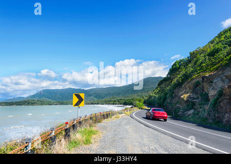 Rotes Auto unterwegs Captain Cook Highway, der malerischen Küstenstraße zwischen Cairns und Port Douglas, Far North Queensland, FNQ, QLD, Australien Stockfoto