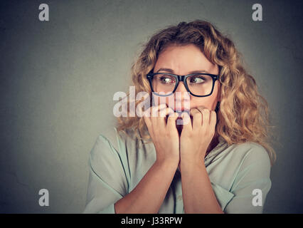 Closeup Portrait nervös betont junge Frau beißen Fingernägel schauen sehnsüchtig verlangen isoliert grau hinterlegt. Menschliche Emotionen Gesicht Ausdruck Gebühr Stockfoto