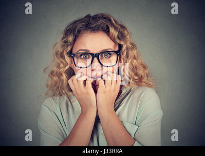 Closeup Portrait nervös betont junge Frau beißen Fingernägel schauen sehnsüchtig verlangen isoliert grau hinterlegt. Menschliche Emotionen Gesicht Ausdruck Gebühr Stockfoto