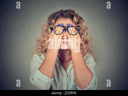 Closeup Portrait junge Frau in Gläsern für Gesicht-Augen benutzen sie beide Hände auf graue Wand Hintergrund isoliert Stockfoto