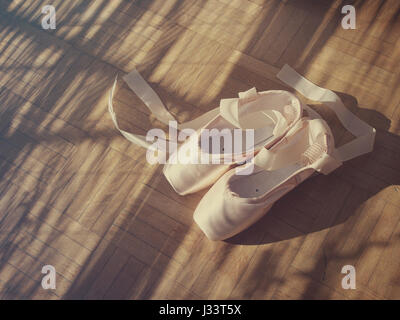 Ballettschuhe und Bänder auf einem Holzfußboden. Stockfoto