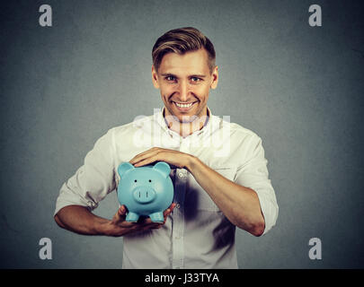 Mann mit Sparschwein auf graue Wand Hintergrund isoliert Stockfoto