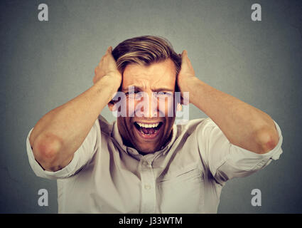 betont Man verärgert, frustriert schreiend auf graue Wand Hintergrund isoliert. Negative Emotionen Stockfoto