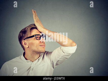 Bedauert Unrecht tun. Dumme junge Mann, slapping Hand am Kopf mit einer duh Moment isoliert auf grauem Hintergrund. Negative menschliche Emotion Gesichtsausdruck Stockfoto