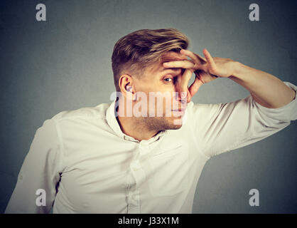 Mann drückt Nase mit den Fingern sieht mit Ekel etwas schlechten Geruch auf grauem Hintergrund isoliert stinkt. Menschliches Gesicht Ausdruck Körpersprache Reaktion Stockfoto