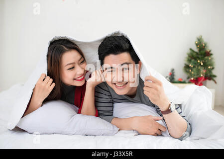 Paar in Liebe teilen, echte Emotionen und Freude am Bett liegen. Stockfoto