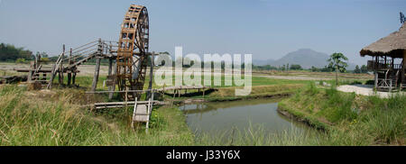 Große hölzerne Turbine Ballenpresse Wasserrad oder Holz Noria Wasser mit Landschaft Reis Feld Gebirge in Chiang Khan in Loei, Thai und Thai Dam Cultural Village Stockfoto