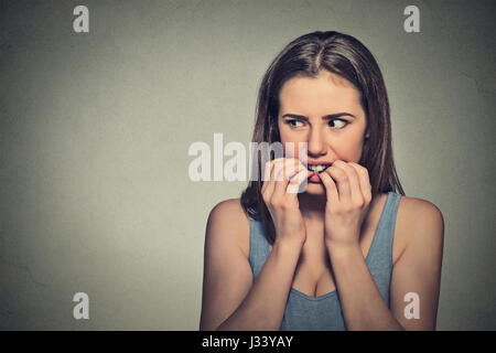 Closeup Portrait junge unsicher zögerlich nervös Frau beißen ihre Fingernägel verlangen nach etwas oder ängstlich, isoliert auf graue Wand Hintergrund. Negati Stockfoto