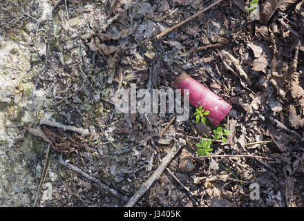 Eine rote verbrachte Schoß leer verworfen fallengelassen Waffe Munition shell Patrone Wurf zertreten in trockener Erde Schlamm Stockfoto