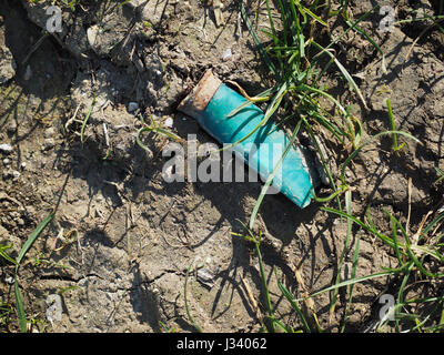 Eine grüne verbrachte Schoß leer verworfen fallengelassen Waffe Munition shell Patrone Wurf zertreten in trockener Erde Schlamm Stockfoto