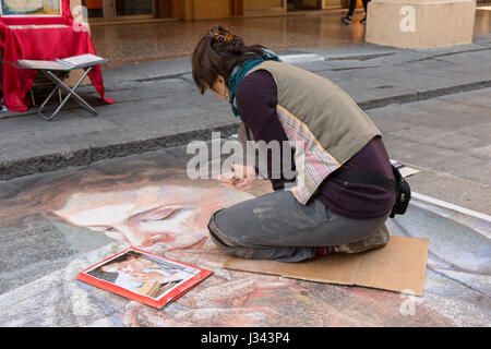 ein junger Streetart-Künstler beim Zeichnen mit Kreide auf dem Bürgersteig Stockfoto