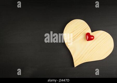 Herz aus Holz auf schwarzem Hintergrund. Wünsche für den Valentinstag. Platz für text Stockfoto