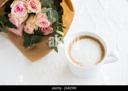 Romantische weibliche Hintergrund mit Kaffee und Rosen auf weiße strukturierte Tabletop, elegante leichte flatlay Stockfoto