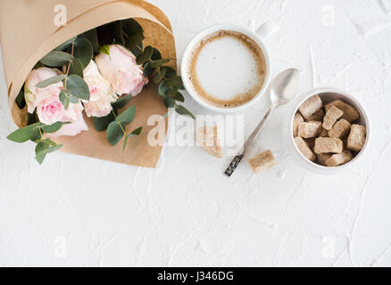 Romantische weibliche Hintergrund mit Kaffee und Rosen auf weiße strukturierte Tabletop, elegante leichte flatlay Stockfoto