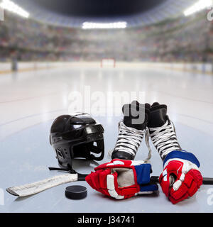 Eishockey-Helm, Handschuhe, Schlittschuhe, Stock und Puck auf dem Eis in fiktiven Arena mit den Fans in den Ständen und Textfreiraum. 3D-Rendering Hockeyarena Eisbahn. Stockfoto